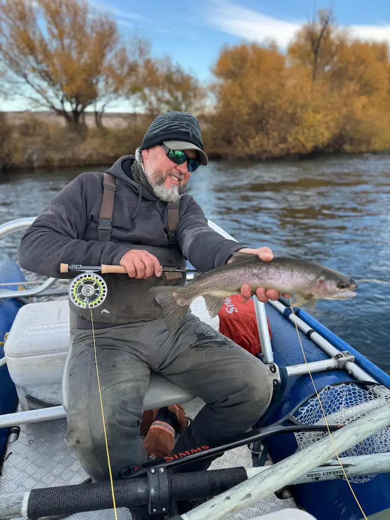 Cristian Patagonia trout fishing guide holding rainbow trout on drift boat