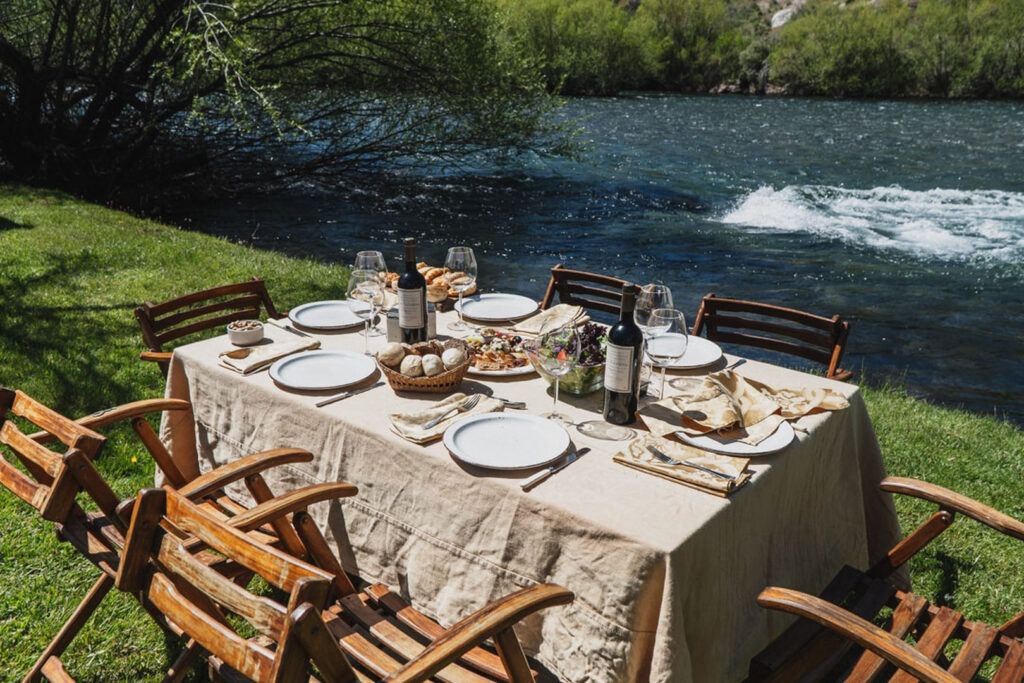 Luxury outdoor dining table setup by river at Stone River Lodge