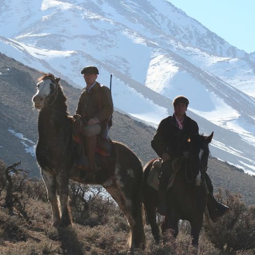 Gauchos horseback riding with snowy Andes mountains background Patagonia