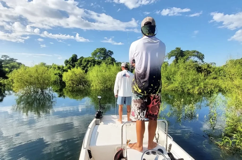 Angler fly casting from boat bow in Argentina wetlands