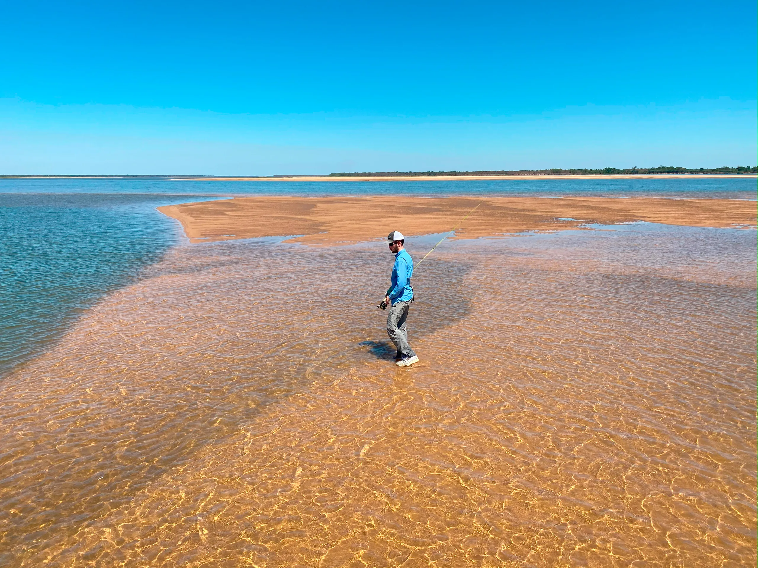 Fly-fisherman wading on a clear sandbar in Argentina